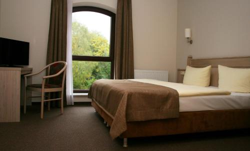 a hotel room with a bed and a window at Landhaus Heinrichshof in Jüterbog