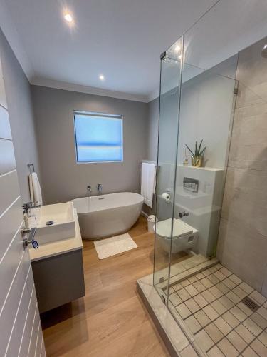 a bathroom with a tub and a sink and a shower at 12 Langdown Ridge in Plettenberg Bay