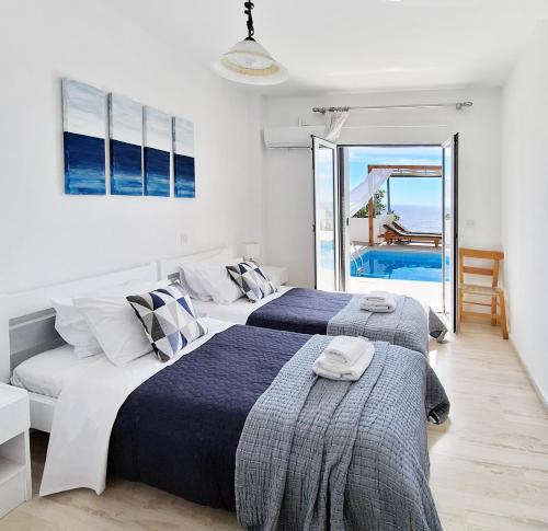 two beds in a bedroom with a view of the ocean at Silver Moon Villa in Achlia