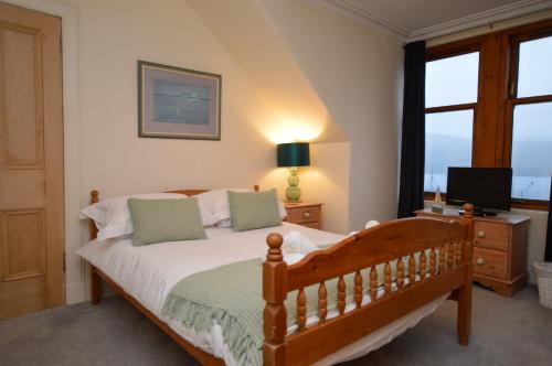 a bedroom with a bed with a television and a window at Aldersyde in Tighnabruaich