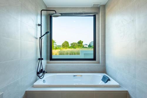 a bath tub in a bathroom with a window at Panmora Poolvilla Sattahip in Ban Tao Than