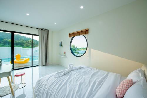 a bedroom with a white bed and a round mirror at Panmora Poolvilla Sattahip in Ban Tao Than