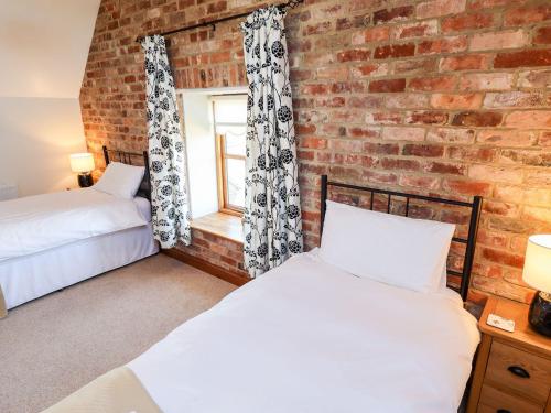 two beds in a room with a brick wall at The Mill House in Louth