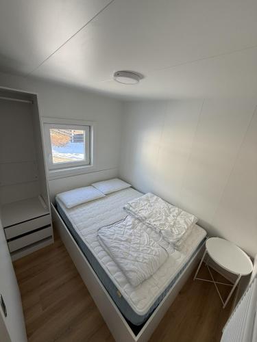 a small white room with a bed and a window at Hiška Moravska ravnica in Moravske-Toplice