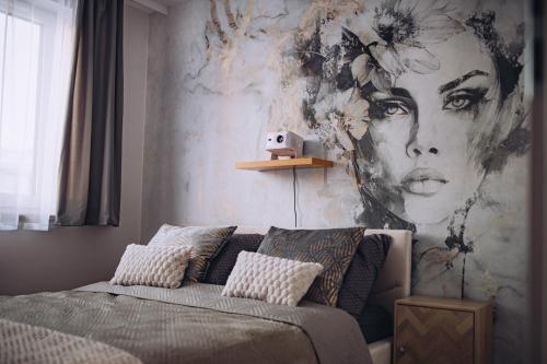 a bedroom with a bed with a painting of a woman at Apartament Panorama Boho in Mława