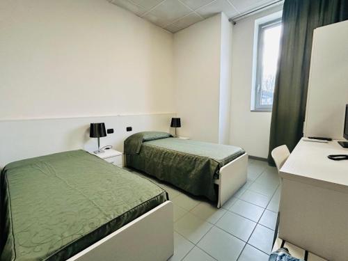 a bedroom with two beds and a desk with a television at The Polo Hub in Mortara