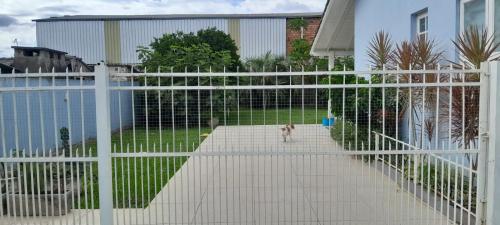 a dog walking through a white fence in a yard at Pantano Casa da Fafá e do Dila in Pântano Grande