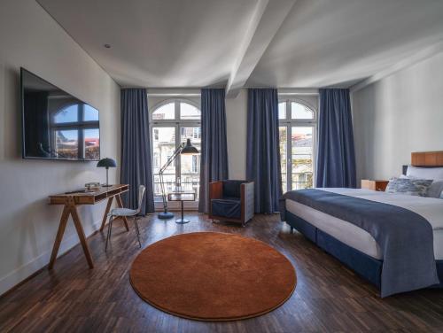 a bedroom with a bed and a desk and windows at Classik Hotel Antonius Köln City in Cologne