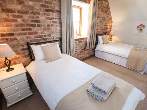 a bedroom with two beds and a brick wall at The Granary in Louth