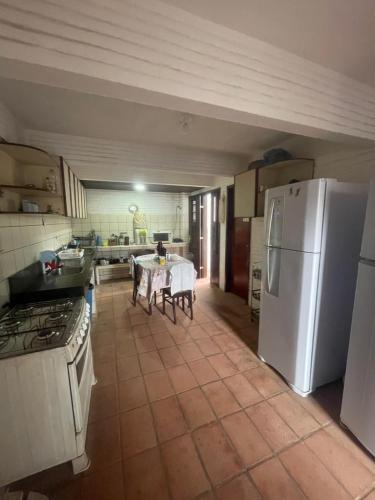a kitchen with a white refrigerator and a table at Casa Vila lagoinha in Lagoinha