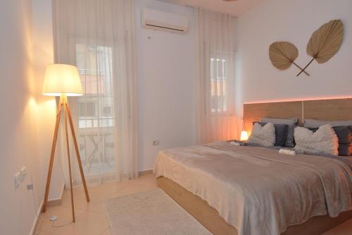 a bedroom with a large bed and a lamp at All Seasons Apartment in Durrës