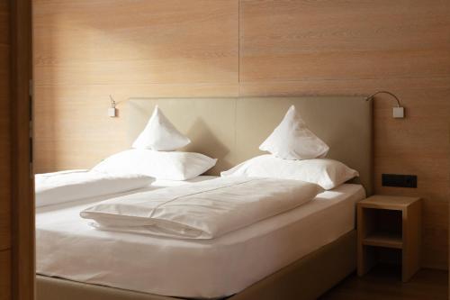 two beds with white pillows sitting next to each other at Gran Tubla Apartments Dolomites in Ortisei