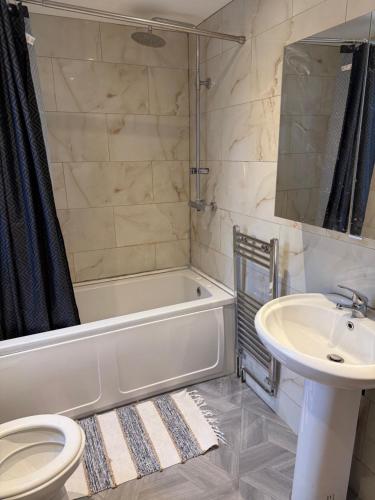 a bathroom with a tub and a sink and a toilet at Luton Town House Near AIRPORT in Luton