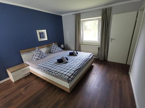 ein Schlafzimmer mit einem Bett, blauen Wänden und einem Fenster in der Unterkunft 06 Grashüpfer - Hof Wiesengrund in Parchtitz