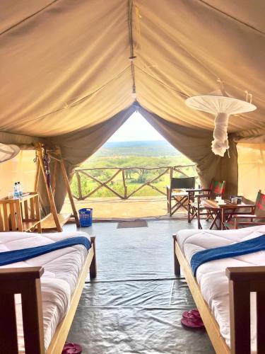 a tent with two beds and a view of the plains at Mara Sunset Acacia Camp in Sekenani