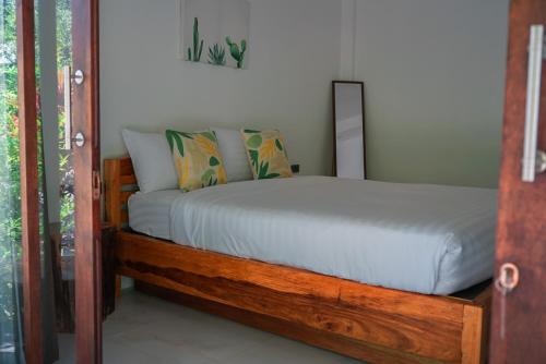 a bedroom with a wooden bed with white sheets at Sweet Room by Maliblue Khanom in Ban Phang Phrao