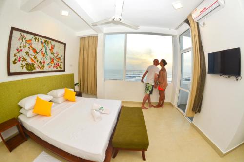 two people standing in a hotel room looking out the window at Ayurvedic Beach Resort in Negombo