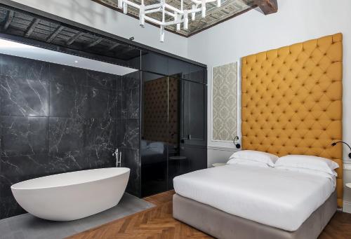 a bedroom with a large white bed and a bath tub at Boutique Centrale Palace Hotel in Rome