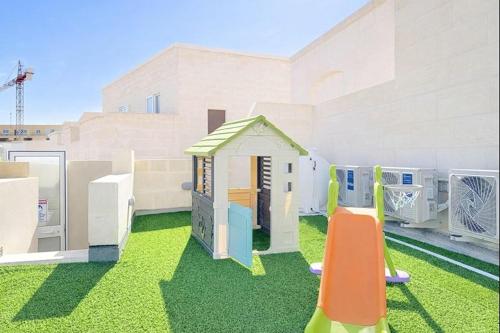 a playground with a toy house on the grass at Peaceful Home with Private Pool and Rooftop Jacuzzi in Xagħra