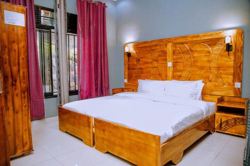 a bedroom with a bed with a wooden headboard at EAR KEN BARHAM GUESTHOUSE in Rwumba