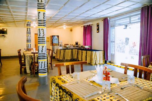 a restaurant with tables and chairs in a room at EAR KEN BARHAM GUESTHOUSE in Rwumba