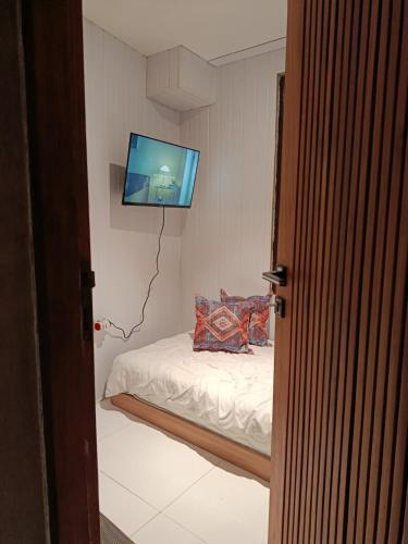 a bedroom with a bed with a tv on the wall at Sanur Backpacker Room Bali in Sanur