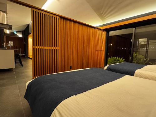 a bedroom with two beds and a kitchen at Ryukyu Garden in Nanjo