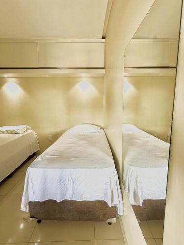 two beds in a room with a mirror at Studio Cafe duas camas de solteiro in Arapiraca