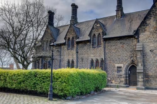 an old brick building with a street light in front of it at Large 6BDR House By Homebird Property Management Short Lets & Serviced Accommodation Leeds With Secured Parking & Garden Area in Leeds