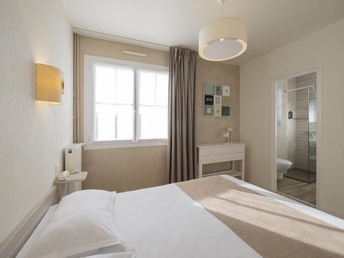 a bedroom with a bed and a window and a bathroom at Hotel Autre Mer in Noirmoutier-en-l'lle