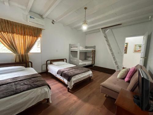 a bedroom with two beds and a tv and a couch at Casa Carito in Cali