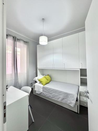 a white bedroom with a bed and a yellow pillow at The Superhost - Duomo Apt in Crotone