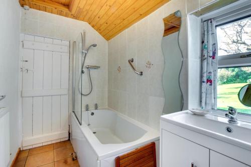 a bathroom with a tub and a shower and a sink at 3 Bed in Gower oc-hh150 in Llangennith