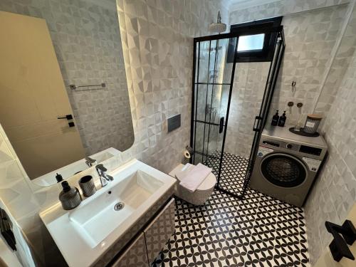 a bathroom with a sink and a washing machine at Stylish Lounge Apartment with Pool & Views in Fethiye