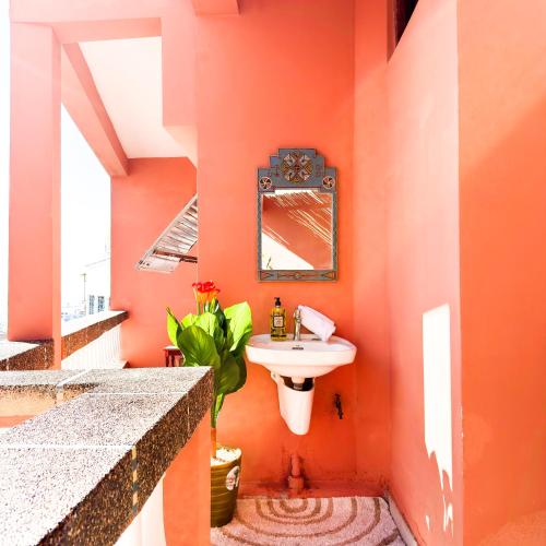 an orange bathroom with a sink and a mirror at Dar Baba Hassan - Ocean View & Ensuite in Taghazout
