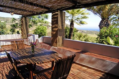 a wooden table and chairs on a deck with the ocean at I Dammusi di Punta Karace in Tracino