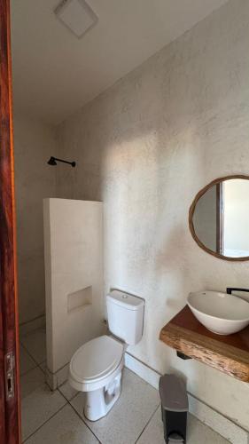a bathroom with a white toilet and a sink at Casa Dunas Baleia in Itapipoca
