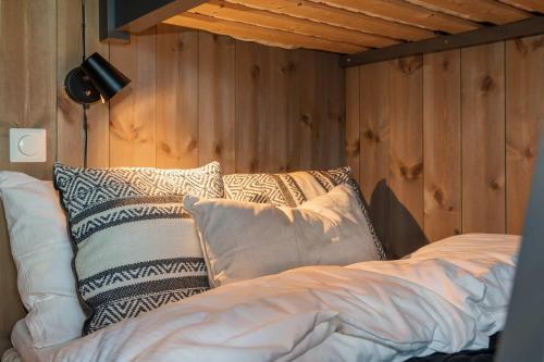 a bed with pillows in a room with wooden walls at TT28- Ski-in out apartment in Trysil turistcenter with sauna in Trysil