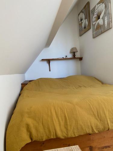 Gîte Dreiviertelacker في Husseren-Wesserling: غرفة نوم بها سرير مغطى ببطانية صفراء