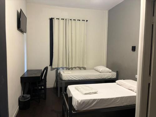 a room with three beds and a table and a desk at Hotel SP Centro by Rede Único in São Paulo