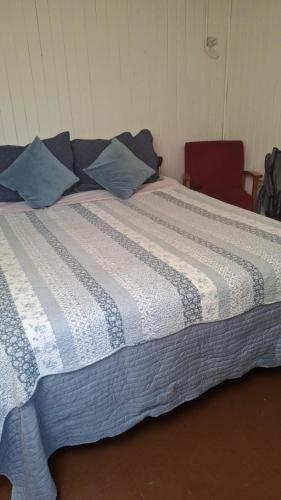 a large bed with a blue and white blanket at Alojamiento MI MOMMA in Osorno