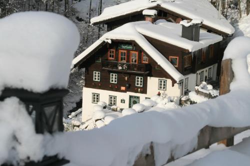 a house covered in snow in front at Hupfmühle Pension in St. Wolfgang