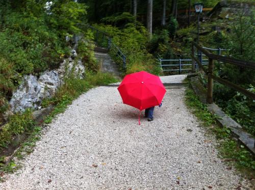 a person with a red umbrella on a gravel road at Hupfmühle Pension in St. Wolfgang