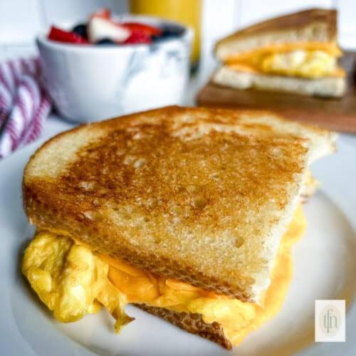 a grilled cheese sandwich on a plate with a bowl of fruit at Sushi guest - mini in Nuwara Eliya