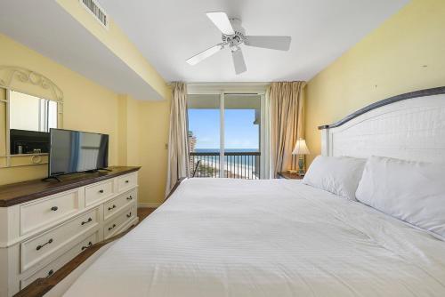 a bedroom with a white bed and a television at Pelican Beach 1216 - Ocean Front Condo with Shared Pool & Beach Access in Destin