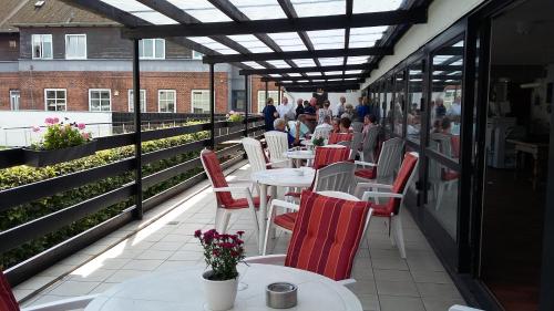 a restaurant with white tables and red chairs and people on a balcony at Hotel Kong Valdemar in Vordingborg