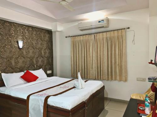 a bedroom with a bed with white sheets and red pillows at Hotel JK Lions - Koradi Road Nagpur in Nagpur
