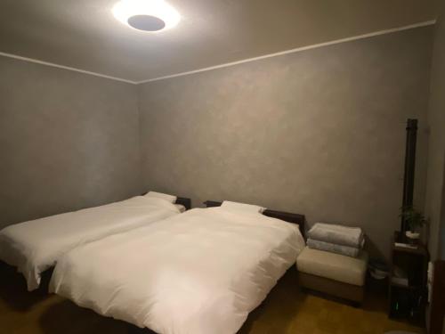 a bedroom with two white beds and a lamp at 夕食ご用意可能guesthouse Yokomachi 街の中心部 静かな通りの一棟貸切 in Shingū