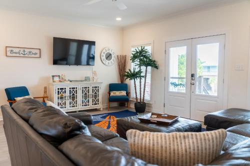 a living room with a leather couch and a tv at Sunset Blessing - 207 Arias Ct in Dauphin Island