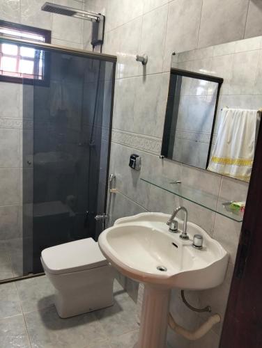 a bathroom with a sink and a toilet and a shower at Quarto em Foz, ótima localização em casa familiar in Foz do Iguaçu